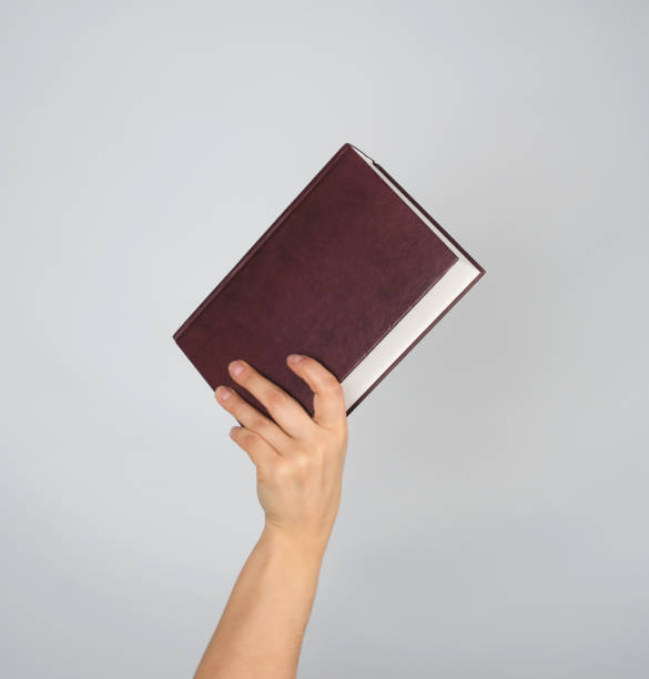istock hand holds a closed book in hardcover 1141224002