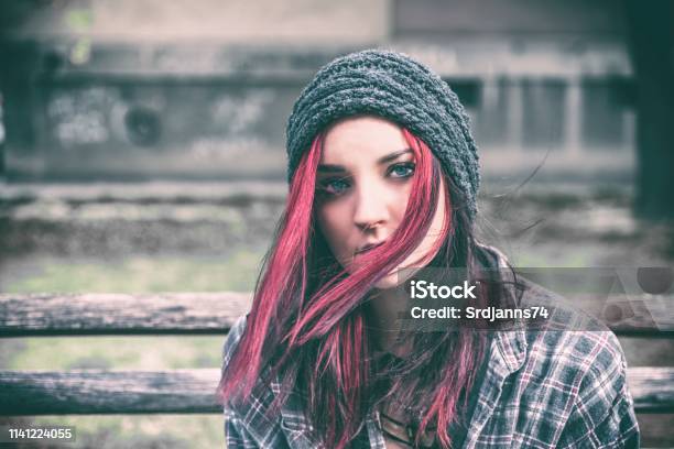 Homeless Girl Young Beautiful Red Hair Girl Sitting Alone Outdoors With Hat And Shirt Feeling Anxious And Depressed After She Became A Homeless Person Close Up Portrait Stock Photo - Download Image Now