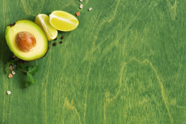 istock Green wooden background with fresh ripe avocado 1141224382