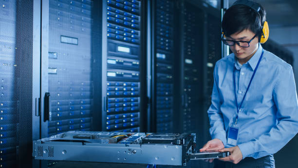 istock In the Modern Data Center: IT Technician Working with Server Racks, on a Pushcart Installing New Hardware. Engineer Doing Maintenance and Diagnostics of the Database. 1141224950