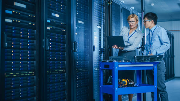 istock In the Modern Data Center: Engineer and IT Specialist Work with Server Racks, on a Pushcart Equipment for Installing New Hardware. Specialists Doing Maintenance and Diagnostics of the Database. 1141224984