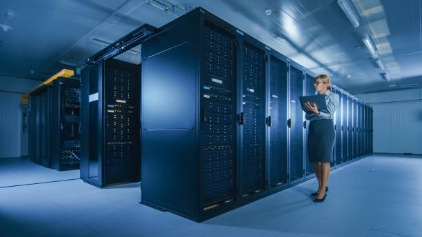 istock In Data Center Female IT Specialist Walks along the Row of Operational Server Racks, Checking Normal Functioning. Modern High-Tech Telecommunications Operational Data Center. 1141225019