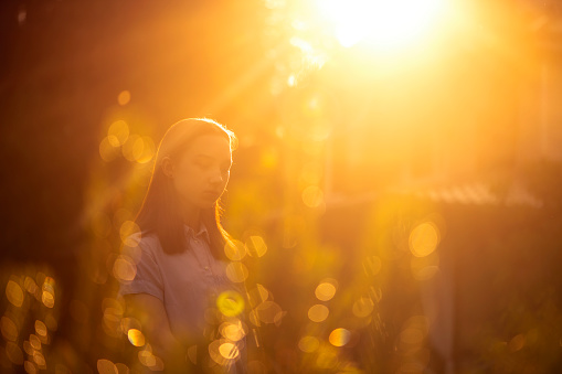 Teen girl standing in garden in sunset in spring or summer