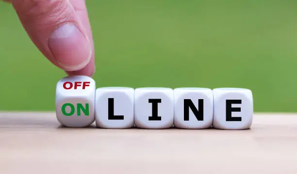 Hand turns a dice and changes the word "offline" to "online" (or vice versa).
