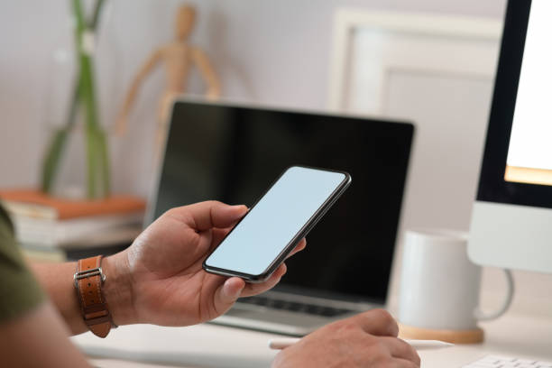 istock Blank screen mock up mobile phone in man hand at home office