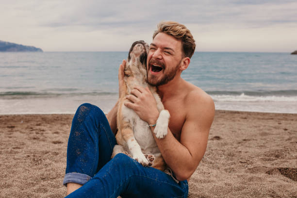 istock Handsome young man holding his puppy at the beach 1141234233