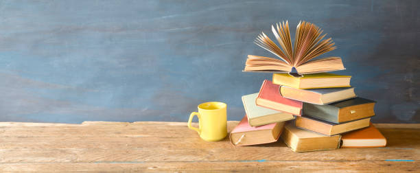 istock open book on a stack of books and a cup of coffee. Reading, learning, education, literature, panorama, good copy space 1141236144