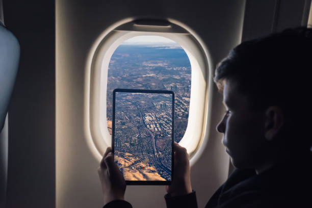istock Caucasian boy using tablet pc taking picture through airplane window Redwood Shores State Marine Park and Foster city. San Francisco. California. USA 1141237848