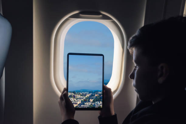 istock Caucasian boy using tablet pc taking picture through airplane window San Francisco cityscape. California. USA 1141237849