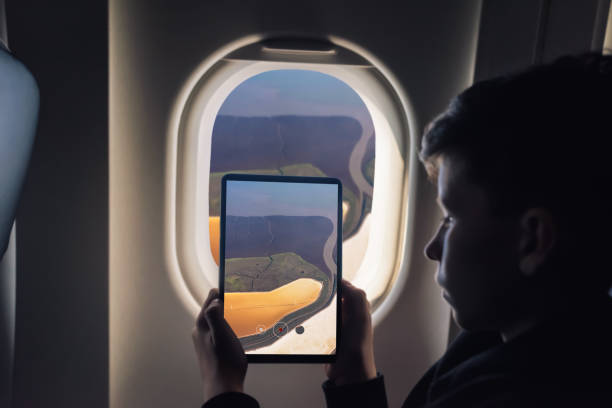 istock Caucasian boy using tablet pc for taking picture through plane window Salt Ponds in Don Edwards. San Francisco Bay National Wildlife Refuge. California. USA 1141237853