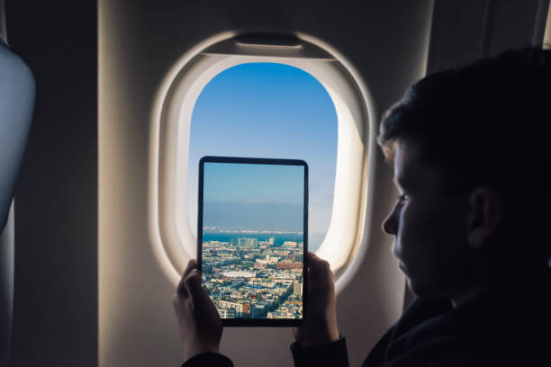 istock Caucasian boy using tablet pc taking picture through airplane window San Francisco cityscape. California. USA 1141237882