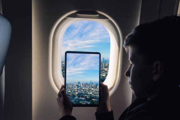 istock Caucasian boy using tablet pc taking picture through airplane window San Francisco cityscape. California. USA 1141237887