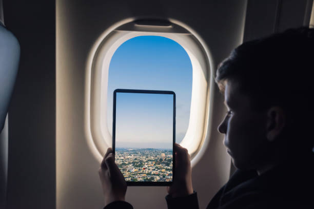 istock Caucasian boy using tablet pc taking picture through airplane window San Francisco cityscape. California. USA 1141237900