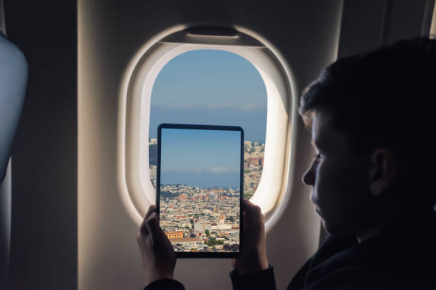 istock Caucasian boy using tablet pc taking picture through airplane window San Francisco cityscape. California. USA 1141237916