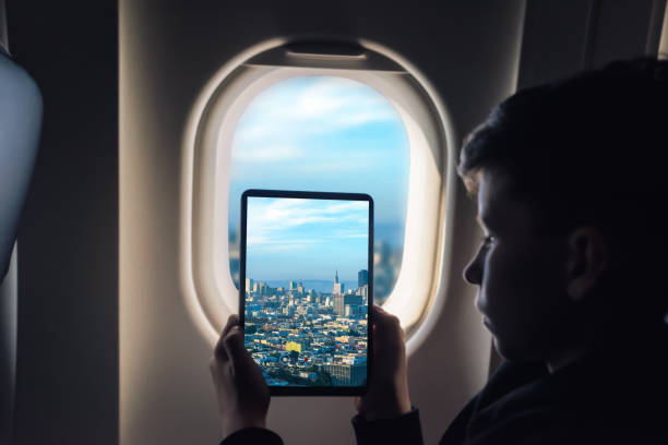istock Caucasian boy using tablet pc taking picture through airplane window San Francisco cityscape with skyscrapers. California. USA 1141237917
