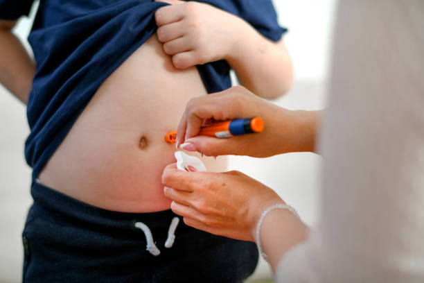 Boy taking an insulin shot at stomach stock photo