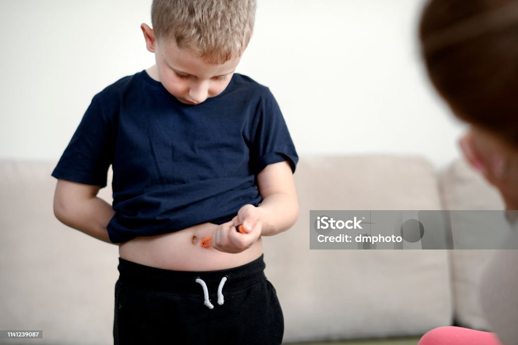 Boy taking an insulin shot Cute blond hair boy taking an insulin shot at stomach 6-7 Years Stock Photo