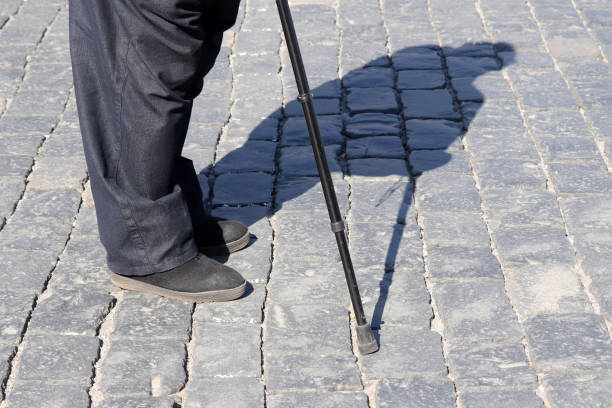 istock Old man standing on a street with walking cane, shadow on pavement 1141239110