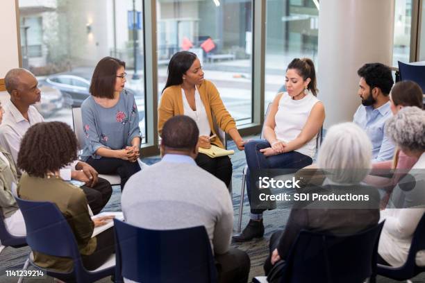 Mental Health Professional Comforts Woman Stock Photo - Download Image Now - Group Therapy, Multiracial Group, Meeting