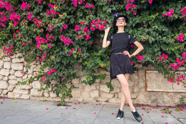 Slim girl outdoors surrounded by flowering plants