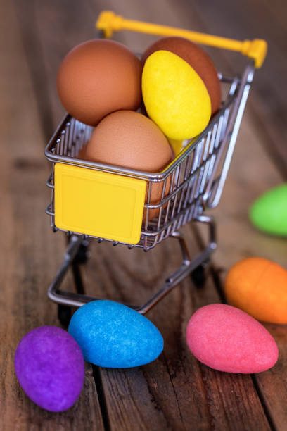 Easter eggs in small shopping cart model at wood table, close-up