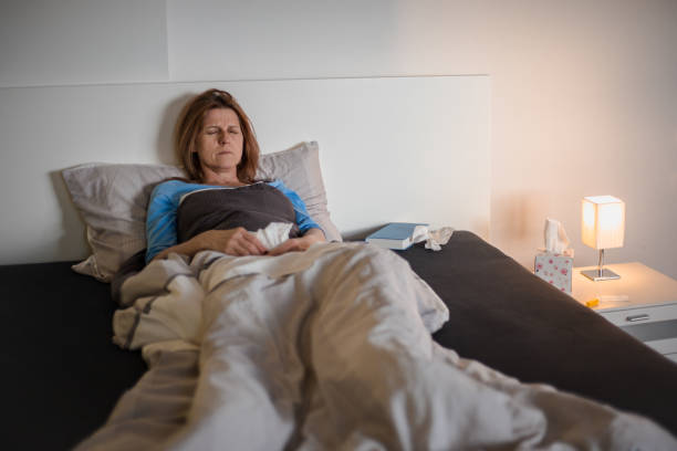istock Woman sick at home, lying in bed, having a headache 1141246349