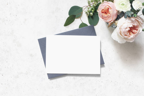 フェミニンな結婚式、誕生日のモックアップシーン。空白の紙のグリーティングカード、封筒。ユーカリの葉の花束、赤面ピンクの英語のバラとラナンキュラスの花。コンクリートテーブル� - birthday card envelope invitation blank ストックフォトと画像