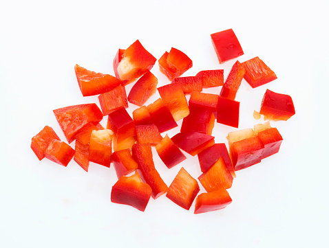 Red bell pepper dices on white background.
