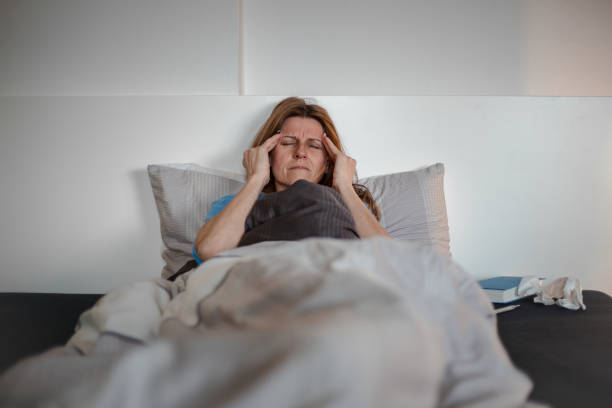 istock Woman sick at home, lying in bed, having a headache 1141246593