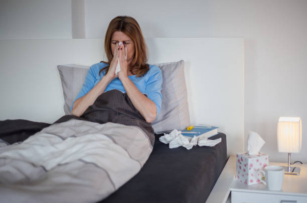 istock Woman lying in bed, having a cold, blowing nose 1141246813