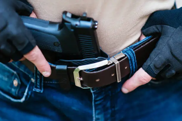 Photo of the guy puts the gun in the holster close-up