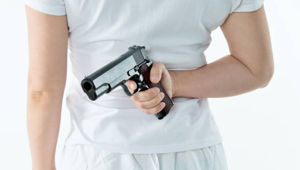 istock Woman hand holding a gun behind back 1141251448
