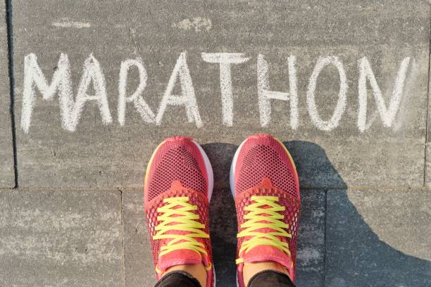 marathon written on gray sidewalk with woman legs in sneakers, top view - female muscular build athlete exercising imagens e fotografias de stock