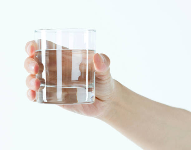 woman hand holding a glass of water - transparent holding glass focus on foreground imagens e fotografias de stock