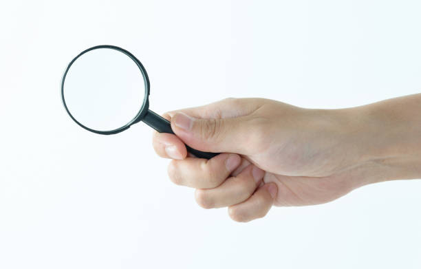 Woman hand holding magnifying glass on white background.