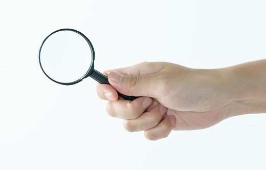 Magnifying glass searching for deals, hand and investigation, search or study with mockup space on white background. Knowledge, source and spy person with analysis, research and reading with problem solving in studio.