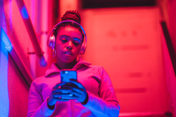 portrait of young black woman listening to music under neon lights - red hair hairstyle dyed hair women imagens e fotografias de stock