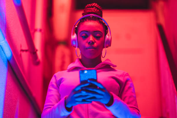 retrato de la joven mujer negra escuchando música bajo luces de neón - letrero de neón fotos fotografías e imágenes de stock
