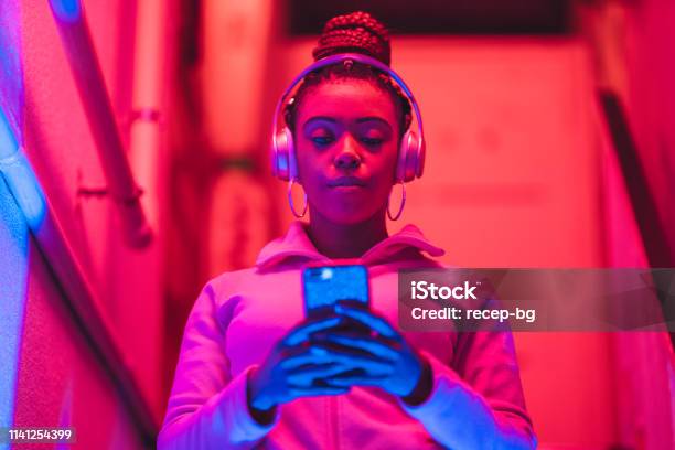 Portrait Of Young Black Woman Listening To Music Under Neon Lights Stock Photo - Download Image Now
