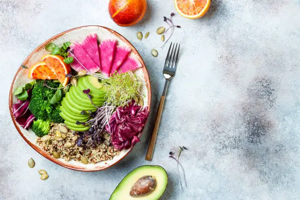 Photo of Vegan, detox Buddha bowl with quinoa, micro greens, avocado, blood orange, broccoli, watermelon radish, alfalfa seed sprouts. Top view, flat lay, copy space