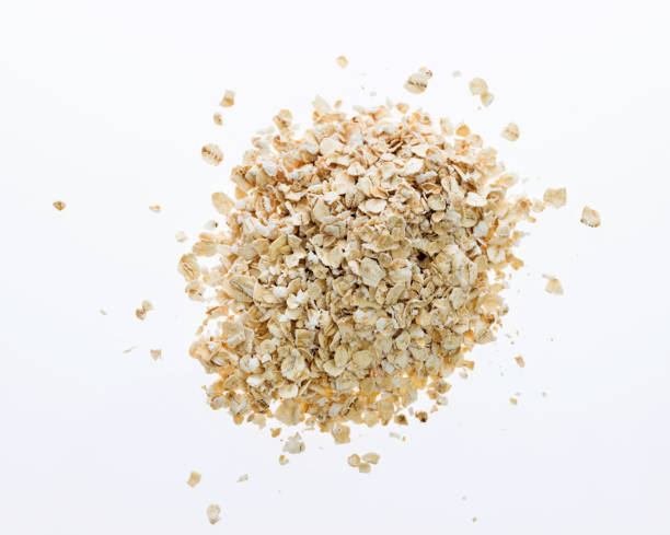 a heap of oat flakes on white background - oatmeal rolled oats oat raw imagens e fotografias de stock