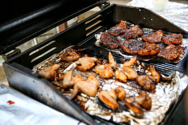 Fried chicken wings with a golden crust lay on a black, greasy grate on the grill. Close-up. Selective focus. Backyard cooking concept