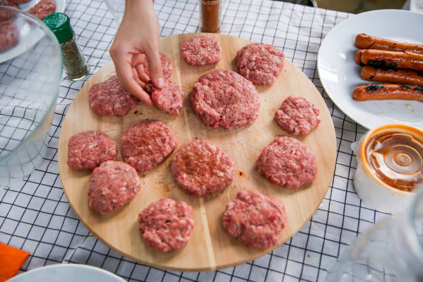 Hamburgers are grilling on a barbecue. Beneath them you can see the fire from the charcoal burning.