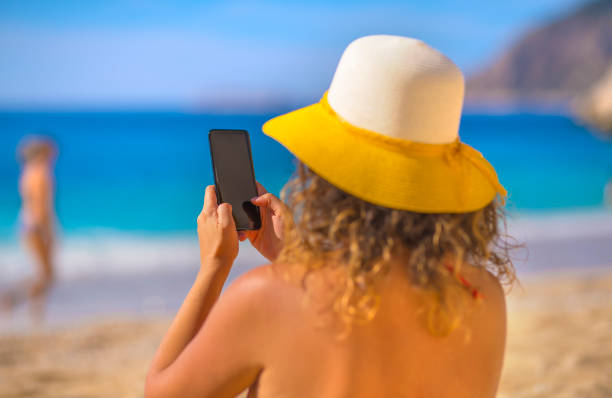 istock Woman using smart phone at beach on summer 1141256434