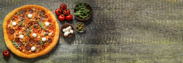 istock pizza with mozzarella, capers, arugula and tomatoes on wooden background 1141258156