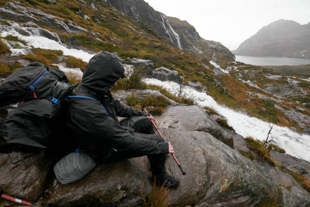 The image was taken on the hike from Sorvagen in Moskenesoya to the mountain Munken with the cabin Munkebu. It was a rainy and stormy day. The hiker is wet and wears outdoor cloths.