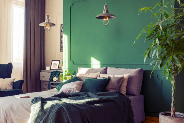 istock Two industrial lamps above comfortable double bed with cozy bedding, copy space on empty wall 1141264325