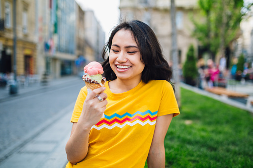 Young Chinese Woman holding an ice cream, enjoying the sweetness.
