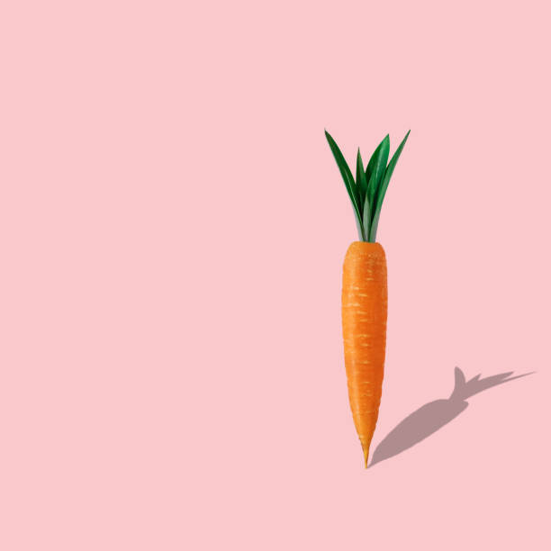 istock Carrot with pineapple leaves on pastel pink background. Minimal Easter composition. 1141270767