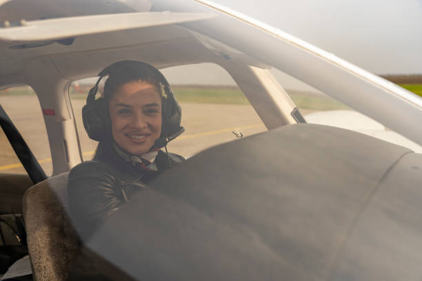 istock Smiling Young Woman Pilot With Headset Looking Through The Cockpit Window 1141276124